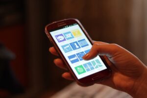A smartphone connected to a laptop with photos transferring on screen