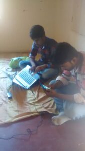 A student using a smartphone beside notebooks and a laptop on a desk